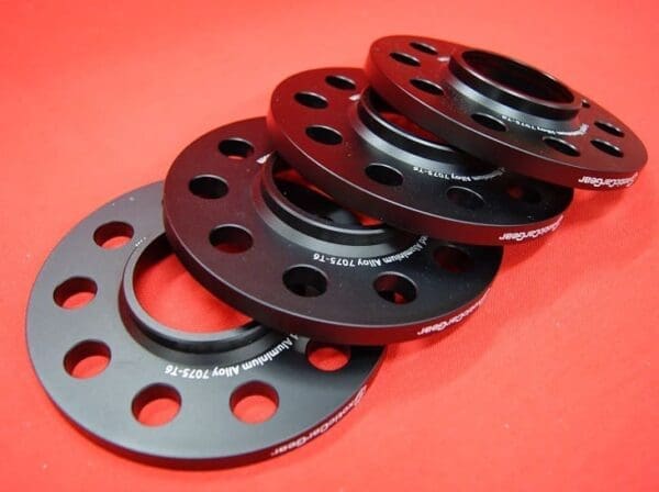 Stack of black aluminum wheel spacers.