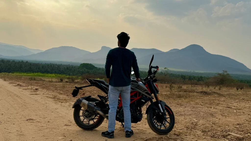 Amar Karthik standing with his KTM Duke 250 at a scenic place