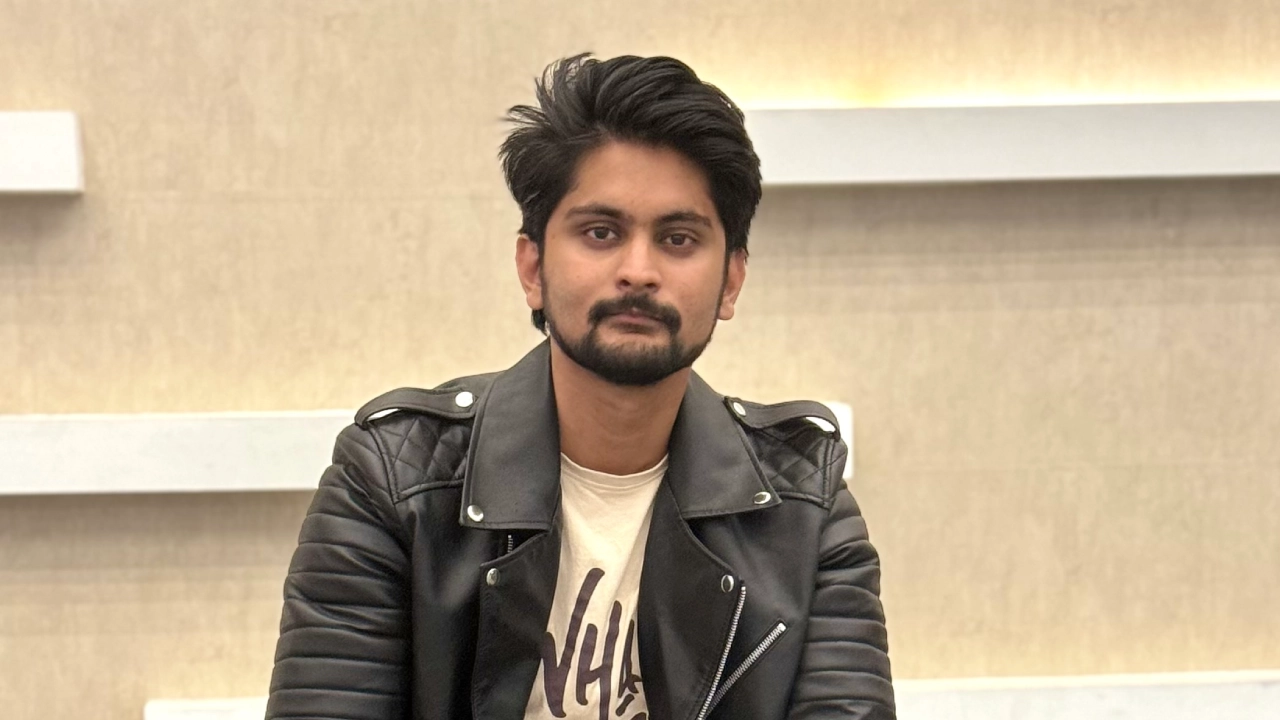 Amar Karthik sitting in a mall with a black leather jacket