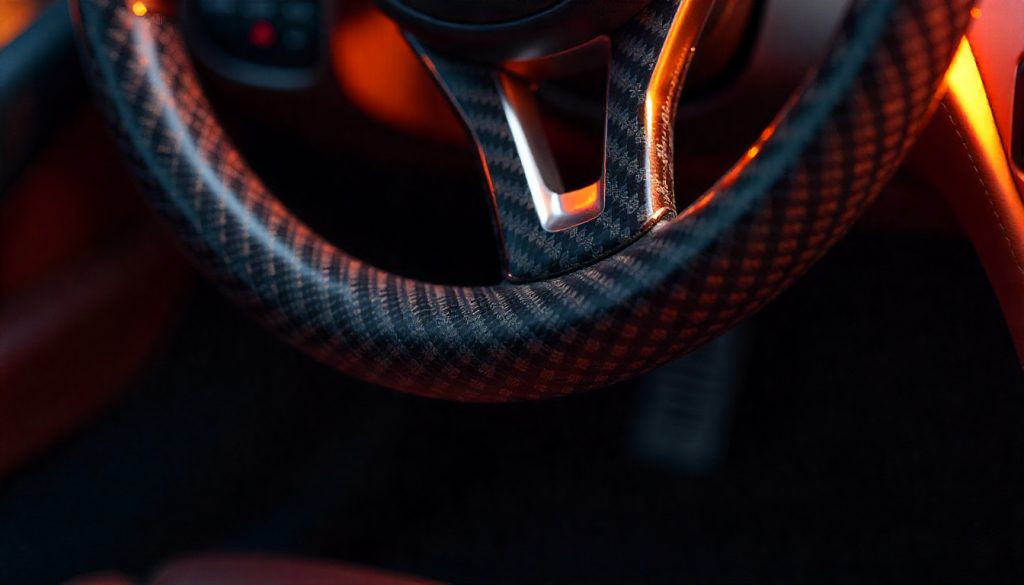 Close-up view of real carbon fiber weave on a luxury car interior, highlighting 3D texture and glossy finish