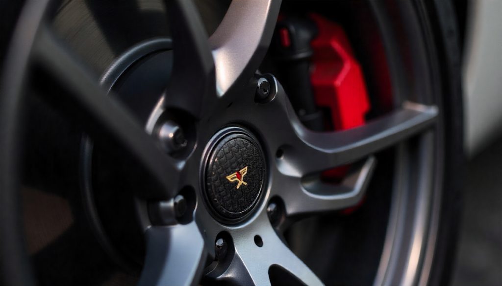 Close-up of carbon fiber tire valve caps on a luxury sports car wheel highlighting premium automotive styling and handcrafted carbon fiber design.